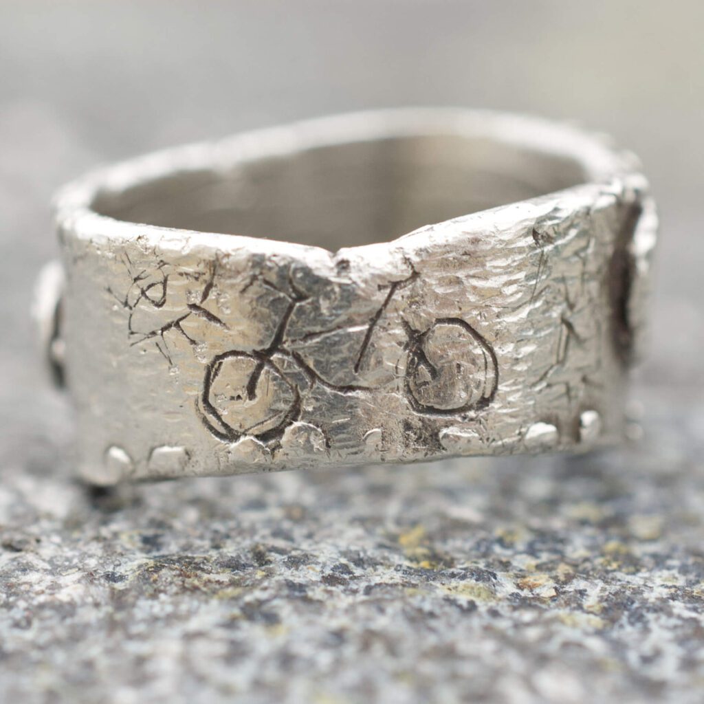 Zadná strana strieborného prsteňa JOYride so symbolmi bicykla a oka