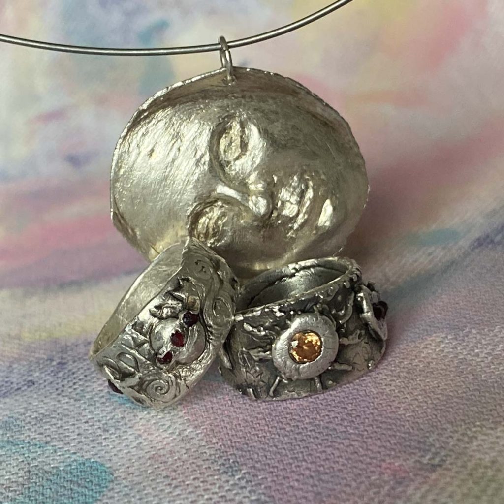 Strieborný talisman súZVUK s detailnými prsteňmi a príveskom, symbolický umelecký šperk.